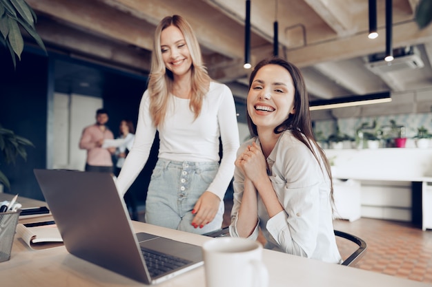 Dos jóvenes empresarias felices celebrando el éxito del proyecto en la oficina