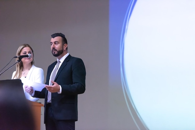 Foto dos jóvenes empresarios dando una presentación a un grupo de colegas sentados en sillas en la sala de conferencias