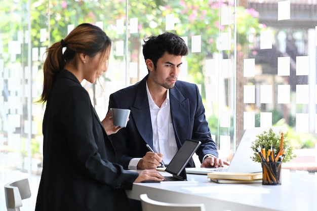 Dos jóvenes empresarios exitosos discutiendo sobre un nuevo proyecto juntos en una oficina moderna y luminosa