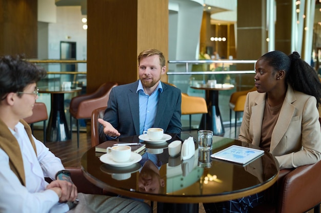 Dos jóvenes empresarios y una mujer negra discutiendo puntos de un nuevo proyecto