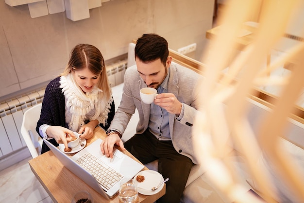 Dos jóvenes empresarios que trabajan en una computadora portátil en un descanso en el café. Vista superior.