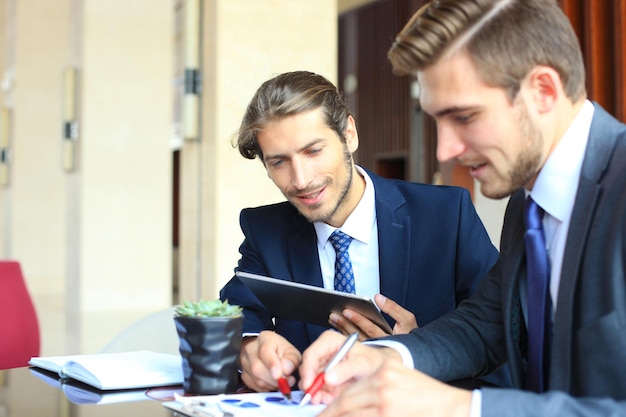 Dos jóvenes empresarios con touchpad en la reunión.