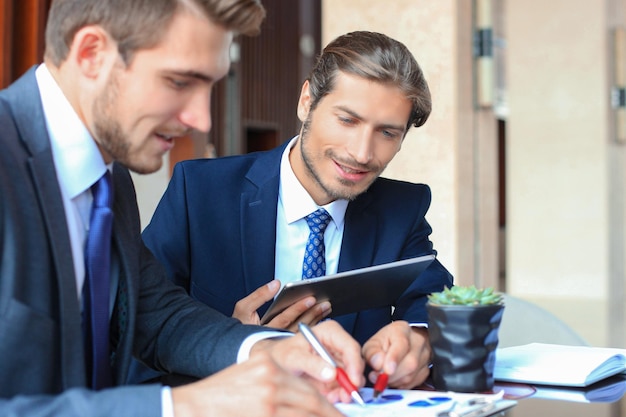 Dos jóvenes empresarios utilizando touchpad en la reunión