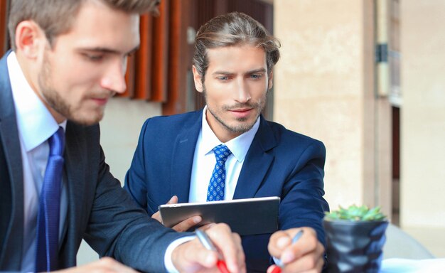 Dos jóvenes empresarios utilizando touchpad en la reunión