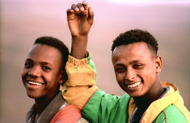 dos jóvenes están sonriendo y levantando las manos