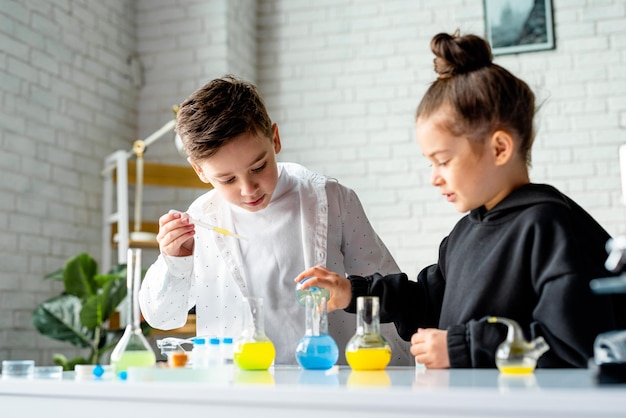 Dos jóvenes estudiantes inteligentes realizan un experimento con un líquido azul en un vaso de precipitados