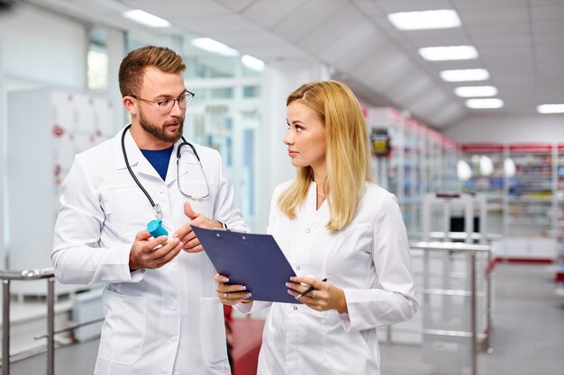 Dos jóvenes farmacéuticos caucásicos están discutiendo la medicación