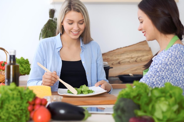 Dos jóvenes felices cocinando en la cocina Amistad y concepto culinario