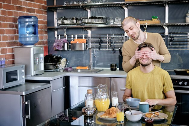 Uno de los dos jóvenes felices que cubren los ojos de su novio con las manos