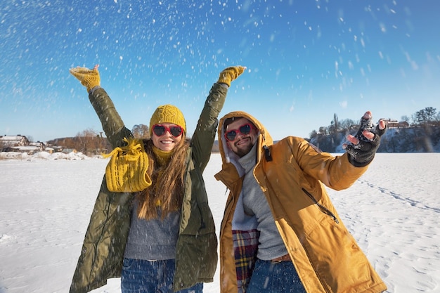 Dos jóvenes felices tirando nieve y divirtiéndose Enfoque selectivo día soleado de invierno