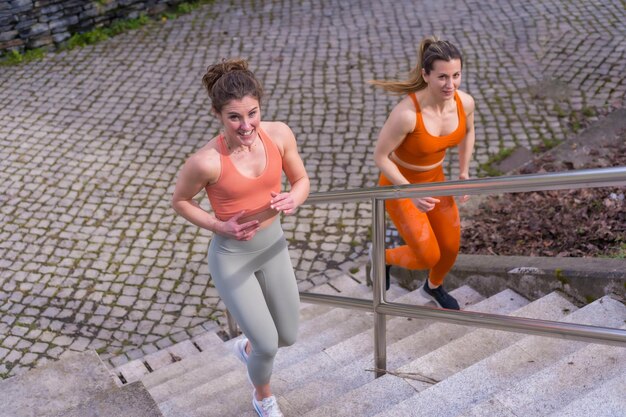 Dos jóvenes fitness en un parque de la ciudad subiendo las escaleras muy rápido y perdiendo calorías