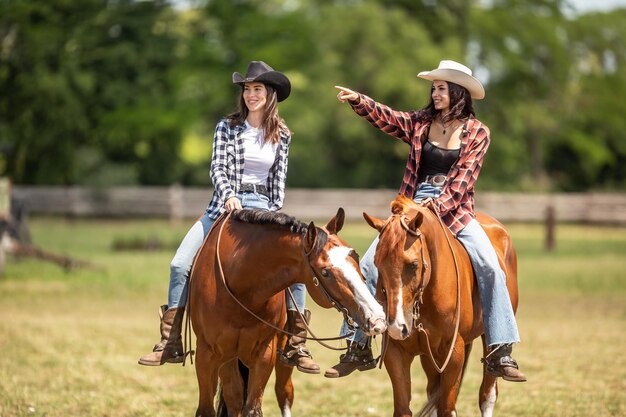 Dos jóvenes guapas montan sus caballos uno apuntando a la derecha mientras los caballos se tocan con los labios