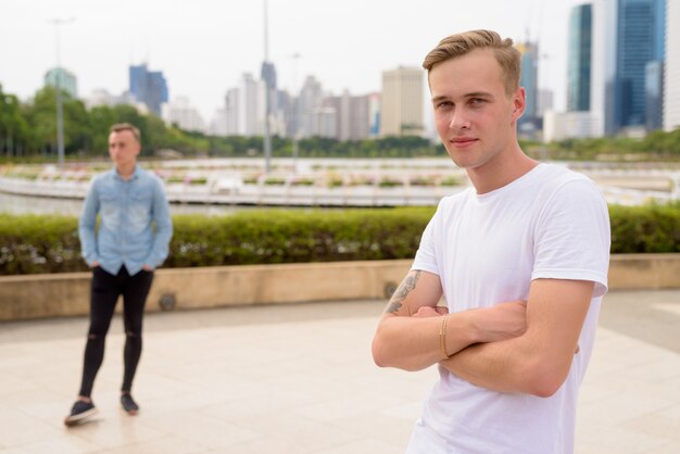 Dos jóvenes guapos con cabello rubio relajándose en el parque