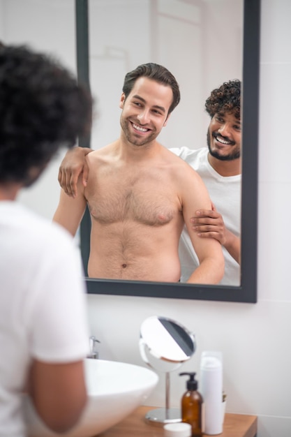 Dos jóvenes guapos parados en el baño frente al espejo