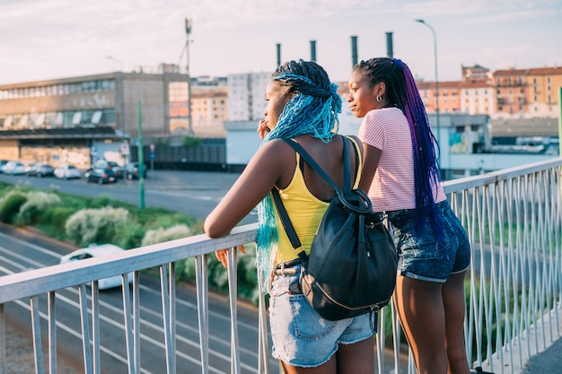 Dos jóvenes hermanas negras hermosas posando al aire libre mirando por encima