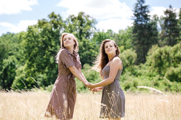 Dos jóvenes hermosas chicas alegres divirtiéndose en la pradera en el parque