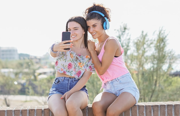 Dos jóvenes hermosas chicas sonrientes tomando una foto selfie