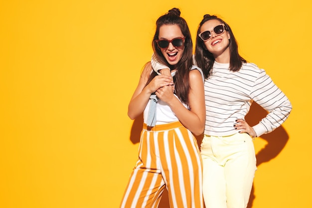 Dos jóvenes hermosas mujeres hipster rubias sonrientes en ropa de verano de moda Mujeres sexy despreocupadas posando en el estudio Modelos positivos divirtiéndose Alegre y feliz