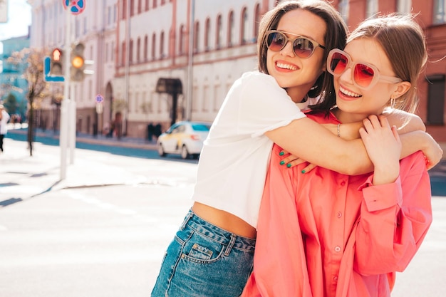 Dos jóvenes hermosas mujeres hipster sonrientes con ropa de verano de moda. Mujeres sexy y despreocupadas posando en la calle. Modelos puros positivos divirtiéndose al atardecer, abrazándose y volviéndose locos. feliz y alegre