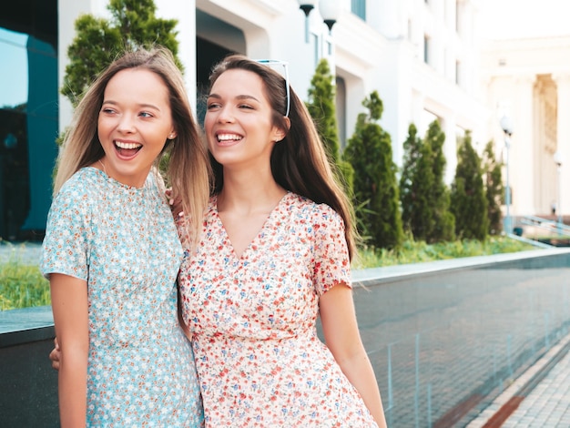 Dos jóvenes hermosas mujeres hipster sonrientes en vestidos de verano de moda Mujeres sexy despreocupadas posando en la calle Modelos puros positivos divirtiéndose al atardecer abrazándose y volviéndose locos