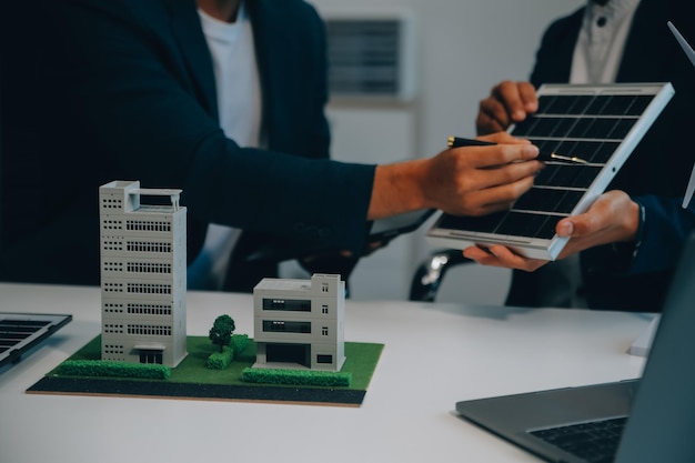 Dos jóvenes ingenieros expertos en la instalación de celdas solares Reuniones y discusión en el trabajo Planificación para instalar paneles solares fotovoltaicos en el techo de la sala de oficinas con plan de construcción de la fábrica