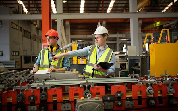 Dos jóvenes ingenieros probando y verificando el funcionamiento de las máquinas de formación de baldosas de chapa metálica