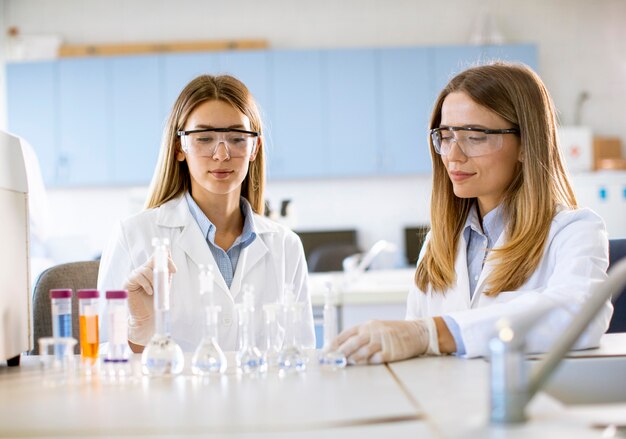 Dos jóvenes investigadoras científicas mirando un frascos con soluciones en un laboratorio