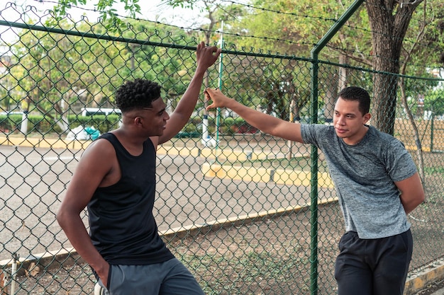 Dos jóvenes latinos en ropa deportiva hablando al aire libre