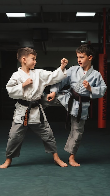 Dos jóvenes luchadores en kimono entrenando artes marciales en el gimnasio