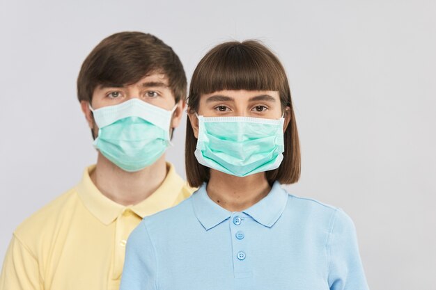 Dos jóvenes con máscara respiratoria de protección en la pared gris