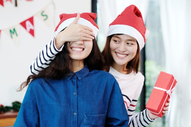 Dos jóvenes mujeres asiáticas dando sorpresa regalo de Navidad