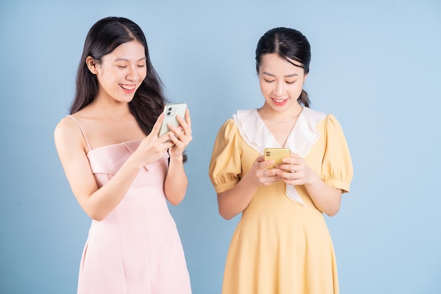 Dos jóvenes mujeres asiáticas vistiendo un vestido sobre fondo azul.