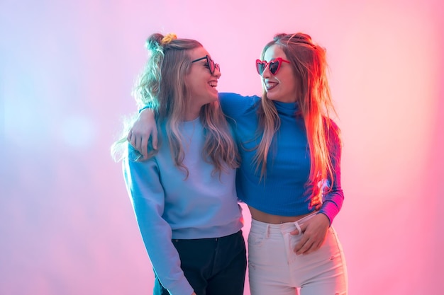 Dos jóvenes mujeres caucásicas rubias bailando en un retrato de discoteca sonriendo y abrazándose