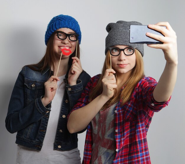 Dos jóvenes mujeres divertidas tomando selfie con teléfono móvil