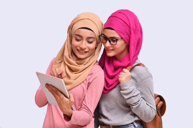 Dos jóvenes musulmanes vistiendo hijab viendo algo en la pestaña modelo paquistaní indio