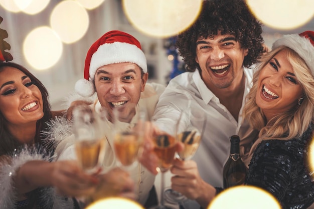 Dos jóvenes parejas alegres celebran el Año Nuevo en casa. Se están divirtiendo y brindando con champán.