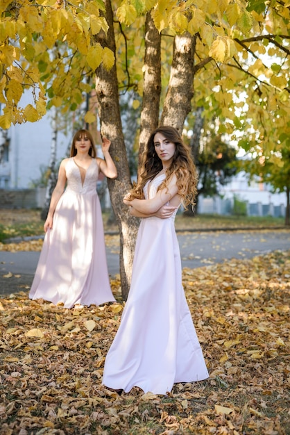 Dos jóvenes princesas con un bonito vestido beige en el parque de otoño. Foto de moda.