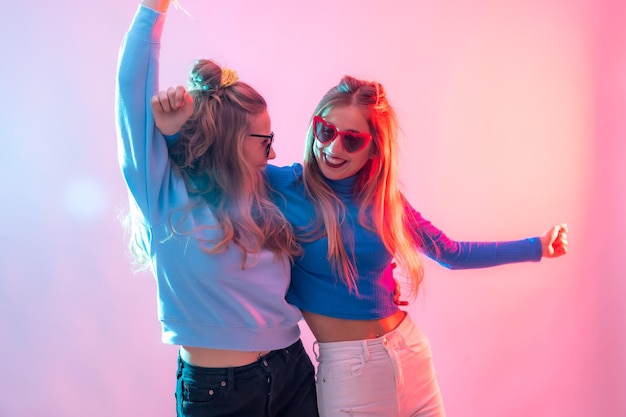 Foto dos jóvenes rubias caucásicas bailando en discoteca sonriendo y divirtiéndose en la fiesta