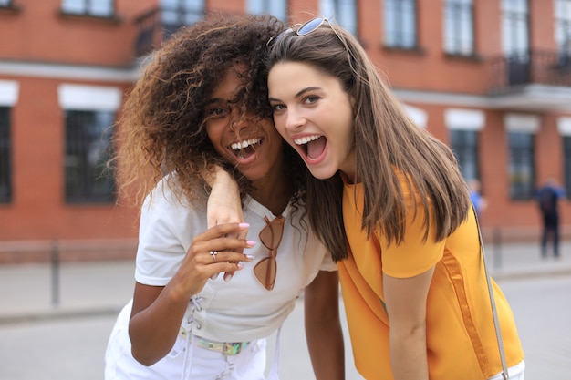 Dos jóvenes sonrientes mujeres hipster en ropa de verano posando en la calle. Mujer mostrando emociones positivas en la cara.