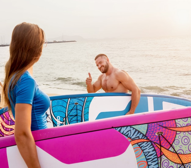 Dos jóvenes surfistas entrando al mar con tablas de surf