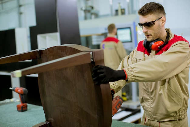 Dos jóvenes trabajadores ensamblando muebles en la fábrica.