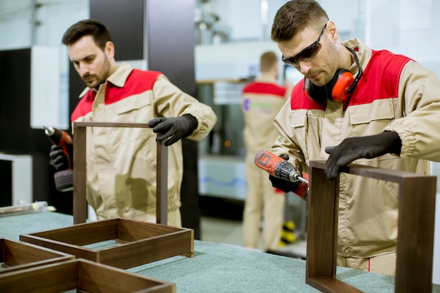 Dos jóvenes trabajadores ensamblando muebles en la fábrica.