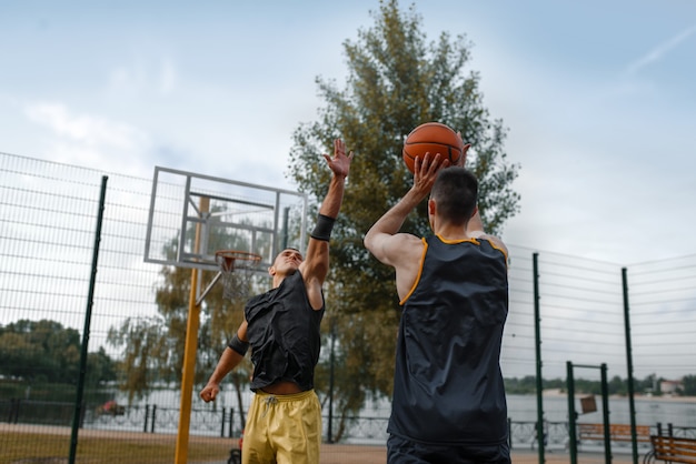 Foto dos jugadores de baloncesto juegan en la cancha al aire libre.