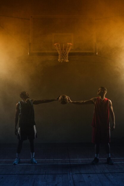 Dos jugadores de baloncesto con una sola pelota de baloncesto