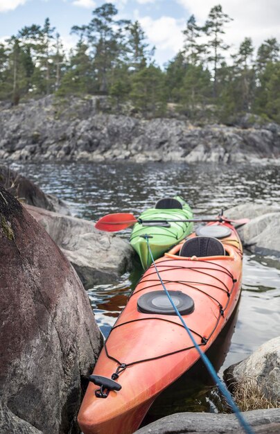 Dos kayaks están amarrados en una costa pedregosa en el fondo de un bosque de acantilados y un cielo