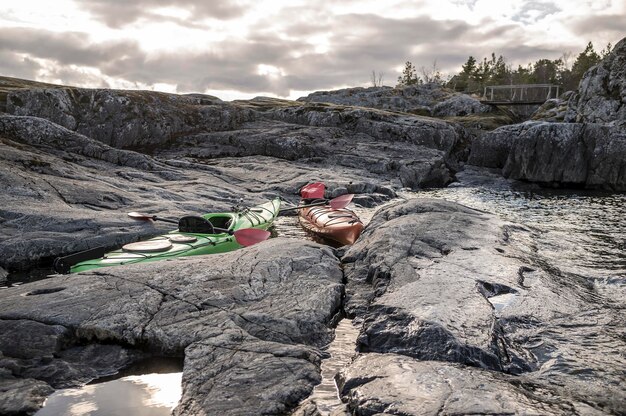 Dos kayaks están amarrados en la costa rocosa en el fondo se puede ver el viejo puente de madera