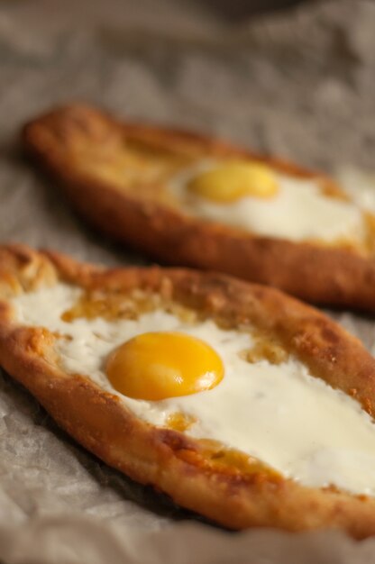 Dos khachapuri Adjarian con yema de huevo encima sobre papel de hornear