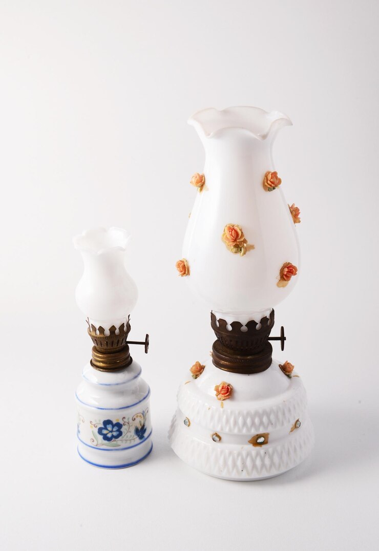 Dos lámparas de aceite de porcelana blanca de época con adornos florales sobre un fondo blanco