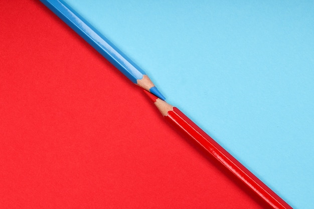 Dos lápices de colores aislados en dos papeles de colores diferentes antecedentes