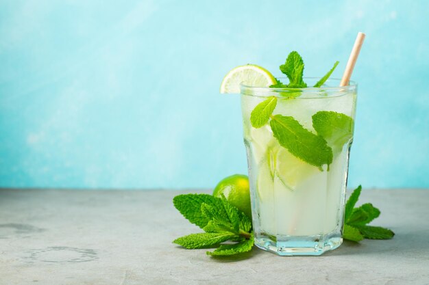 Dos limonadas caseras o cócteles de mojito con menta de lima y cubitos de hielo en un vaso en una mesa de piedra ligera bebida fresca de verano con espacio para copiar